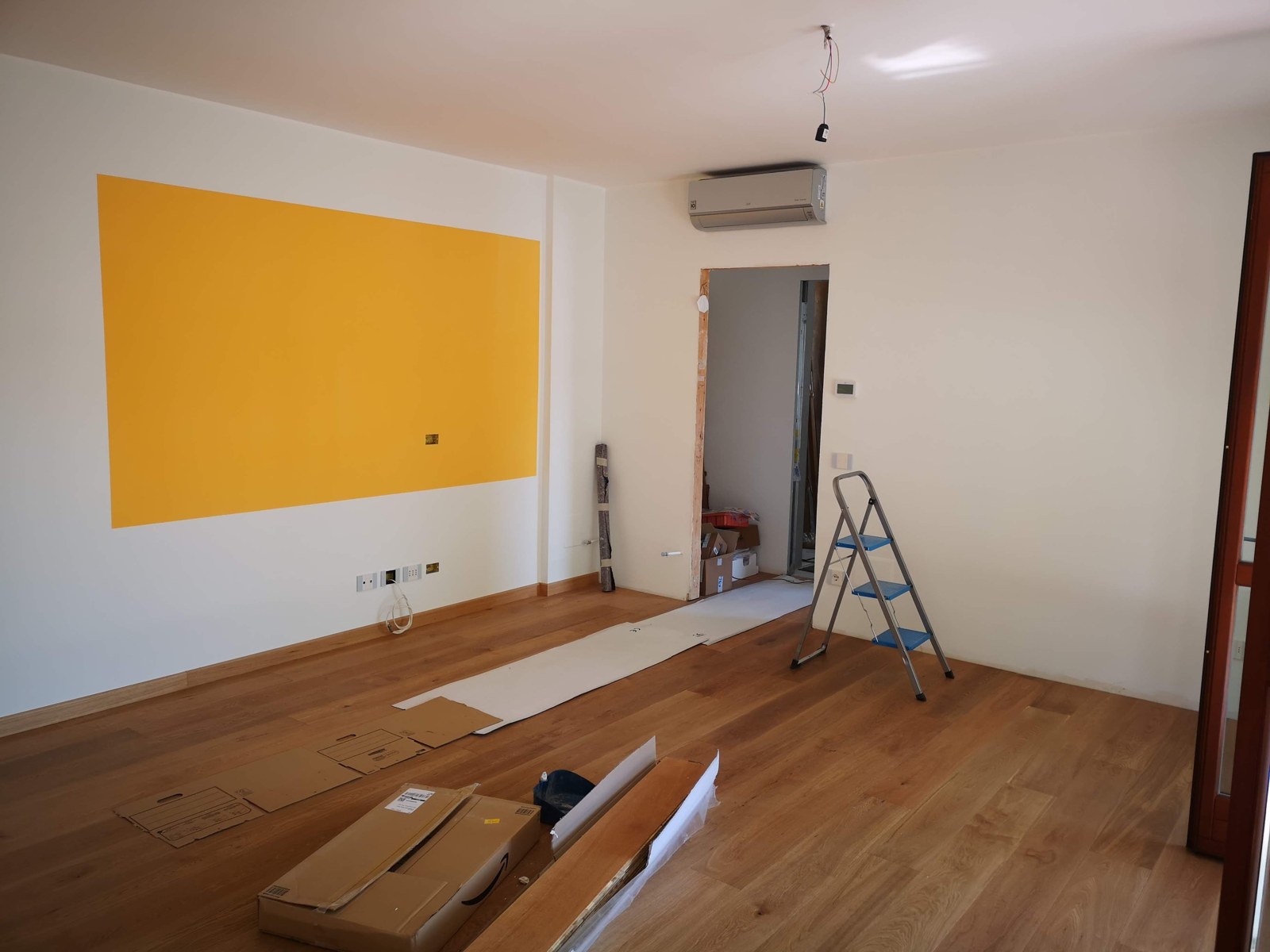 A room undergoing renovation with a ladder and materials on the floor