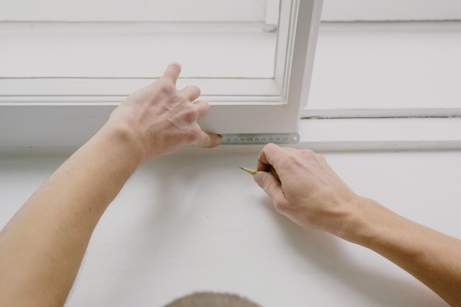 Hands using a ruler while checking a window frame inside a room
